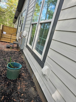 A house with a wooden deck, a green pot with plants, and a window with a view of trees. - The SideSuite-Private Entrance-Clarks Hill Lake & Augusta (Appling)