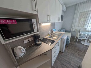 Une petite cuisine équipée d’un four à micro-ondes, d’une machine à café, d’une bouilloire et d’un évier.