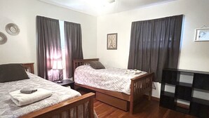 A room with two wooden beds, a small table, a lamp, and a framed picture on the wall. - Hometown Cozy  ADA friendly, Kids, Pets, King Bed! Quiet, Safe Neighborhood (Medina)