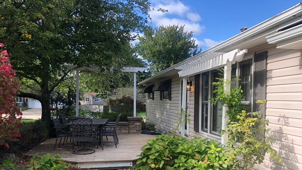 A patio with a table and chairs, surrounded by greenery and a stone wall. - Hometown Cozy  ADA friendly, Kids, Pets, King Bed! Quiet, Safe Neighborhood (Medina)
