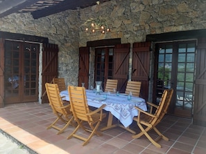 A stone patio with a table set for four, surrounded by wooden chairs. - Prachtige villa met privézwembad (Fayence)