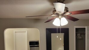 A bedroom with a bed, a ceiling fan, a wardrobe, and a built-in microwave.