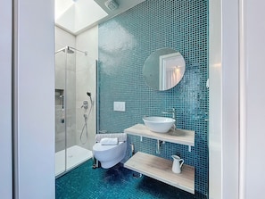 A bathroom with a glass shower enclosure, a toilet, a sink with a mirror, and a blue-tiled wall. - Mar Yam View by Atlantic Holiday (Santana)