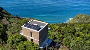 A modern building with solar panels on the roof, surrounded by lush greenery and overlooking a coastline. - Mar Yam Garden by Atlantic Holiday (Santana)
