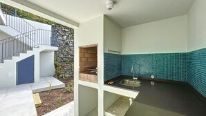 A modern kitchen with a built-in grill, a sink, and a staircase leading to an outdoor area. - Mar Yam Garden by Atlantic Holiday (Santana)