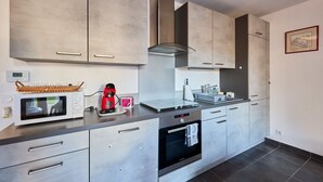 A modern kitchen with stainless steel appliances, grey cabinets, and a built-in oven. - Les Anémones de Langrune - Avec jardin clos (Langrune-sur-Mer)