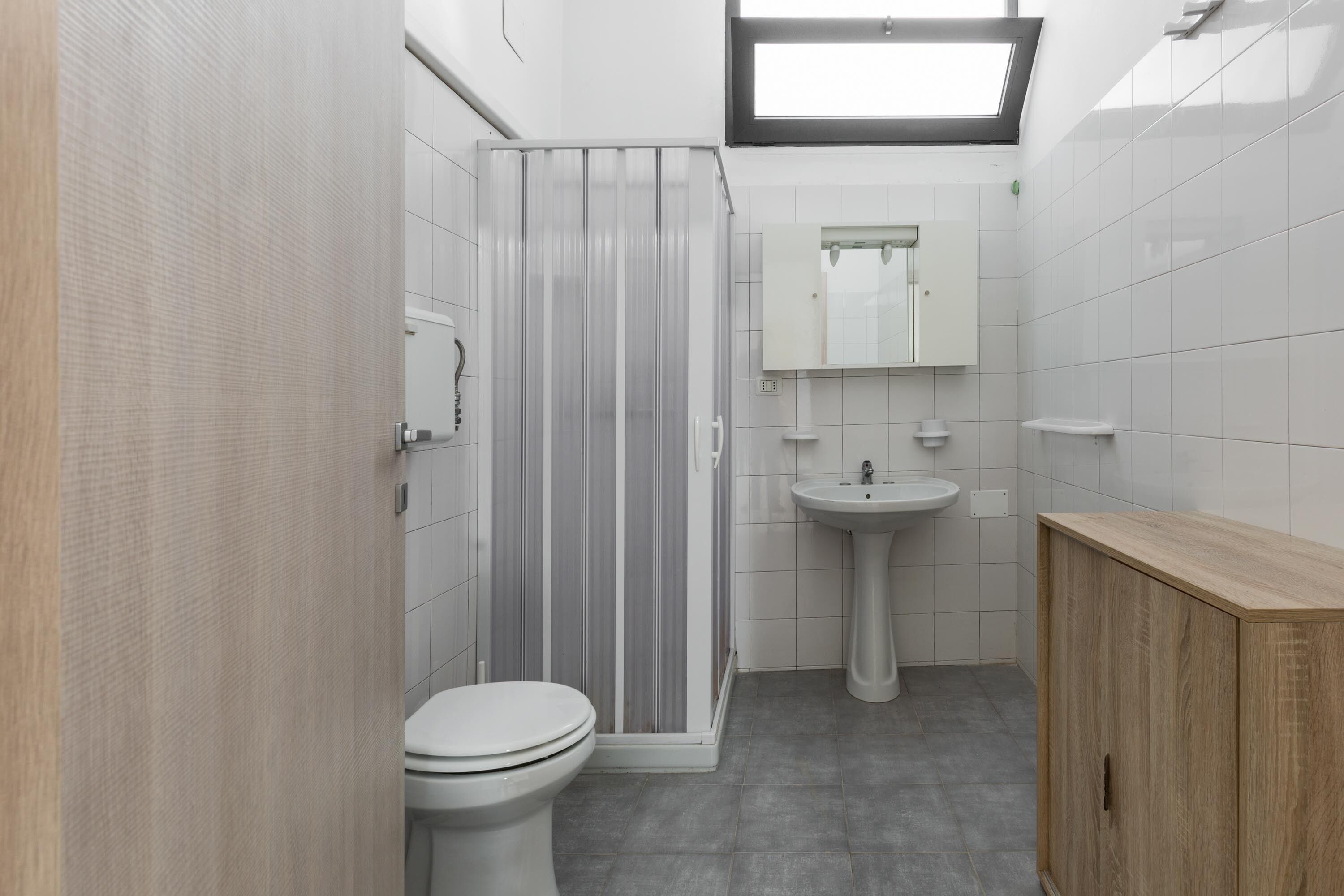 Ein modernes Badezimmer mit Dusche, Toilette, Waschbecken und Holzschrank.