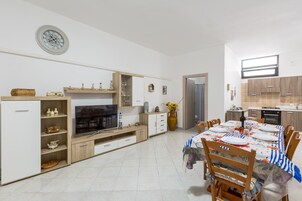 Una cocina moderna con comedor, televisor y un reloj en la pared.