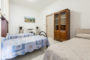 A bedroom with two beds, a wooden wardrobe, a desk with a chair, and a painting on the wall. - 3827 Sabbiabianca - Aptm D by Barbarhouse (Porto Cesareo)