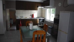 Una cocina compacta con armarios oscuros, un refrigerador blanco y una mesa de comedor con sillas.