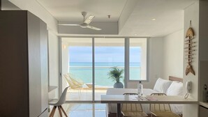 A modern room with a balcony, a ceiling fan, a bed, a table with chairs, and a view of the ocean. - Wynwood Cartagena Beach (Cartagena)