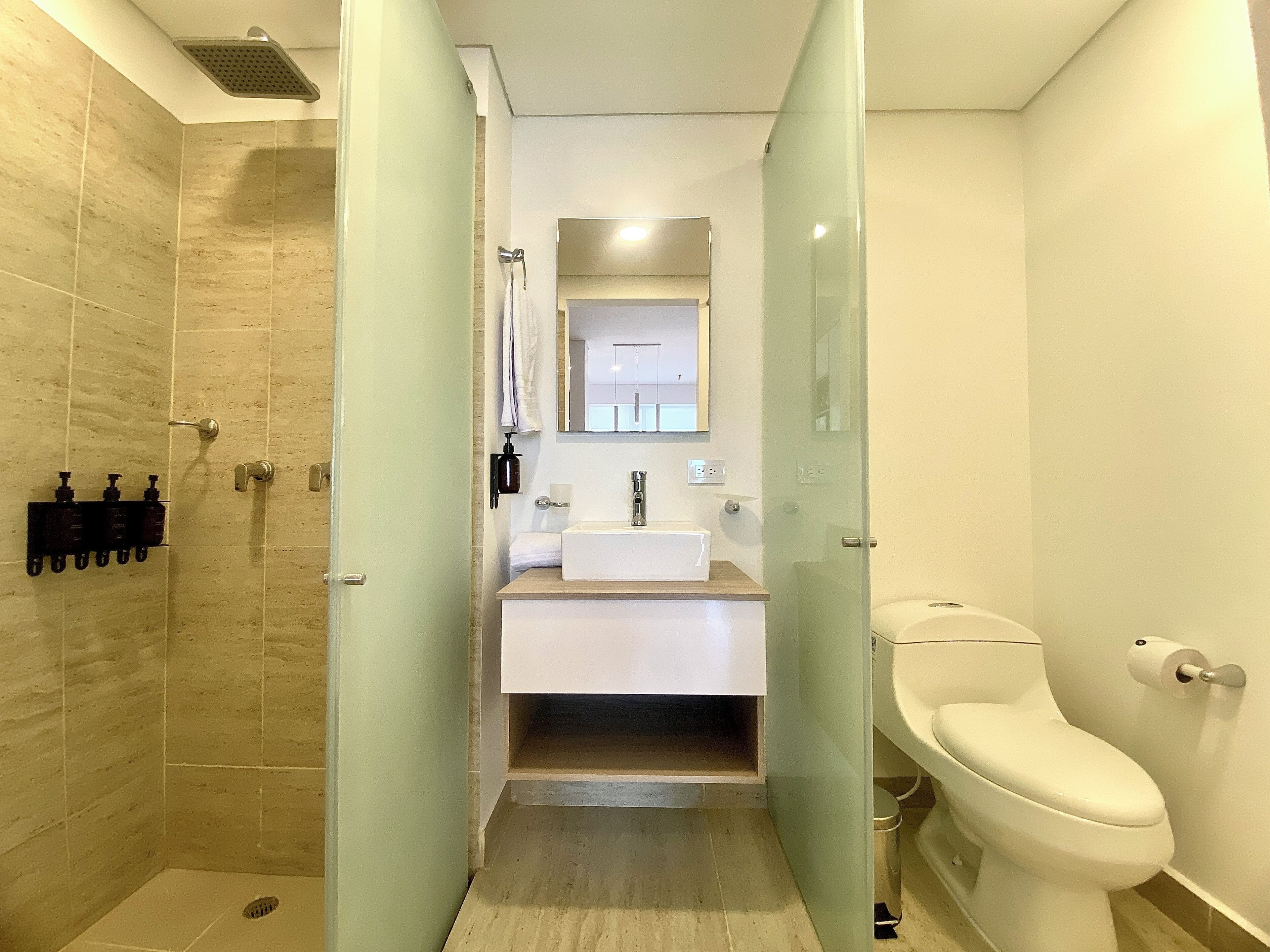 Een moderne badkamer met douche, wastafel en toilet.
