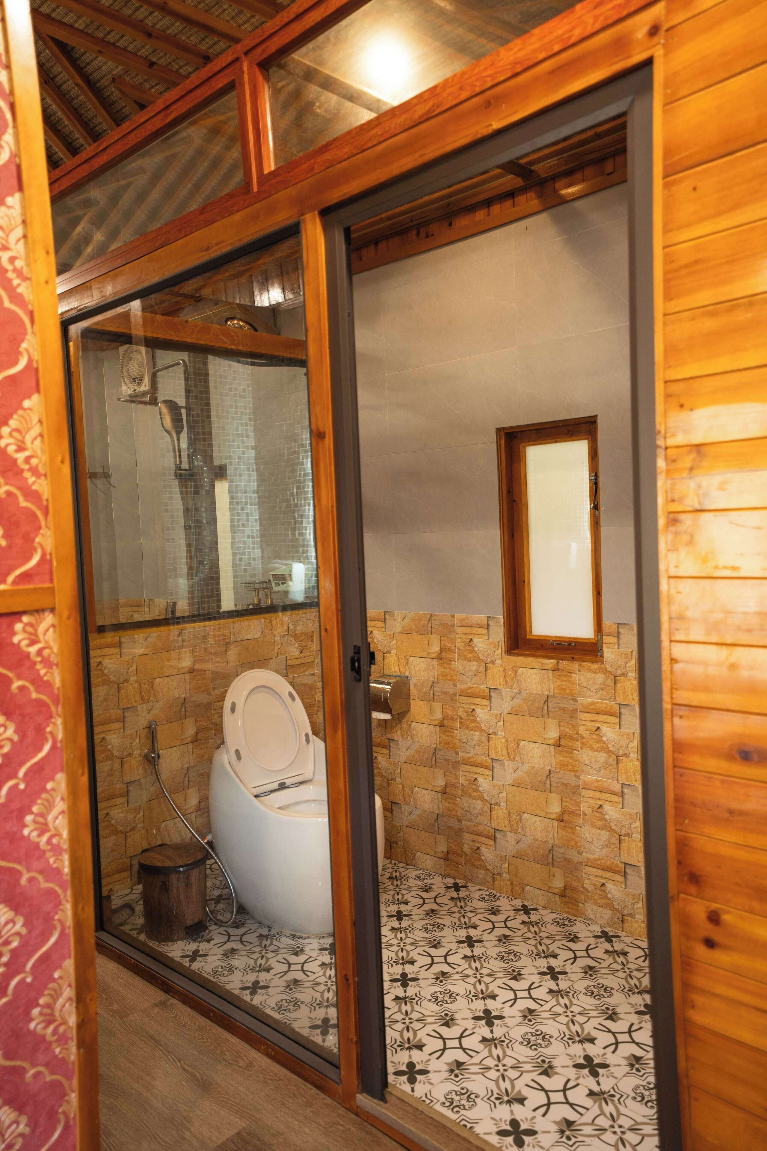 Interior de madera con inodoro, ducha y suelo de baldosas.