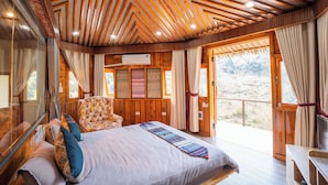 A wooden-paneled bedroom with a large bed, a chair, and a desk. There is a window with curtains and a view of the outdoors. - Sinai Bungalow & Hotel SaPa (Sa Pa)