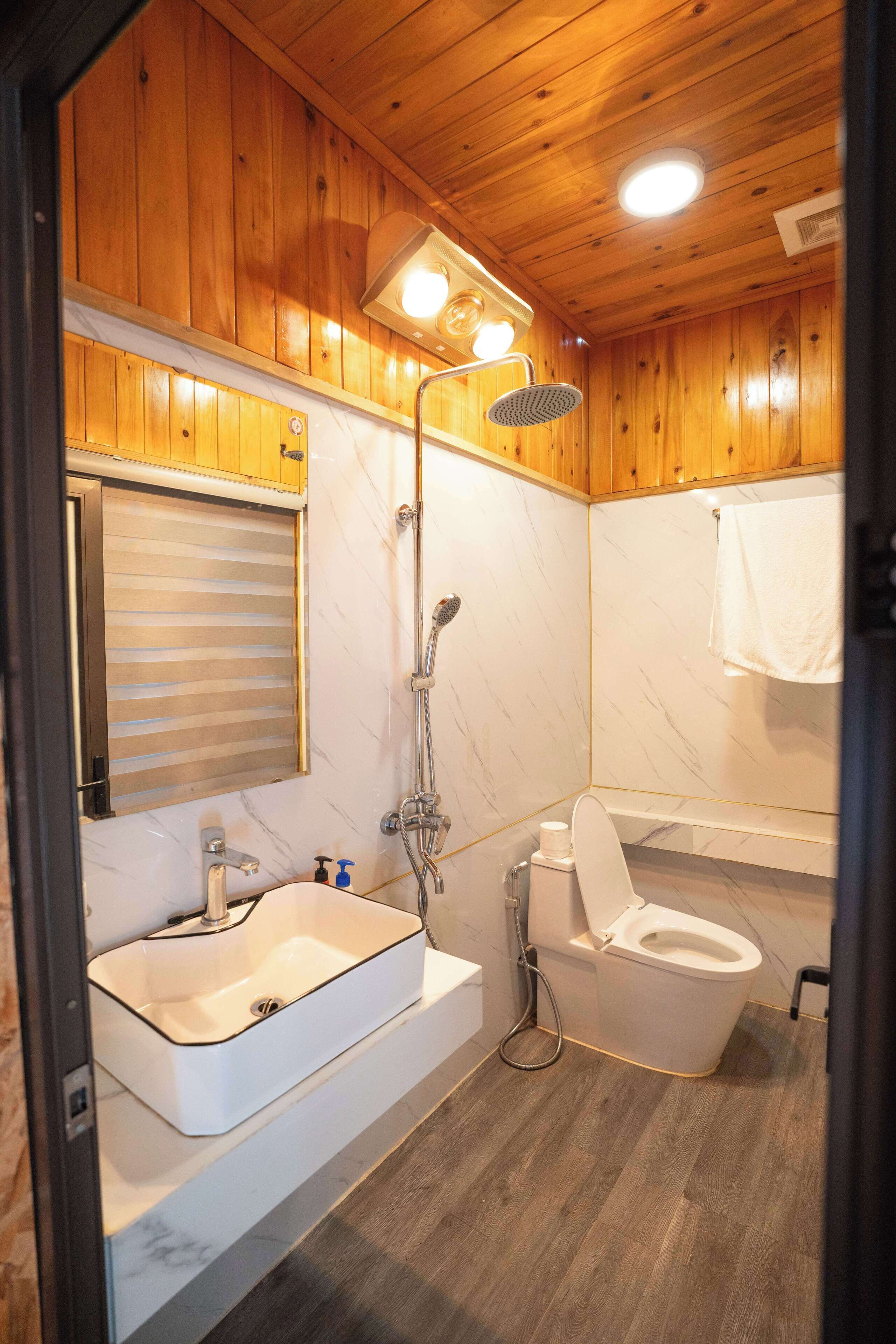 A wooden-paneled bathroom with a sink, toilet, and shower.