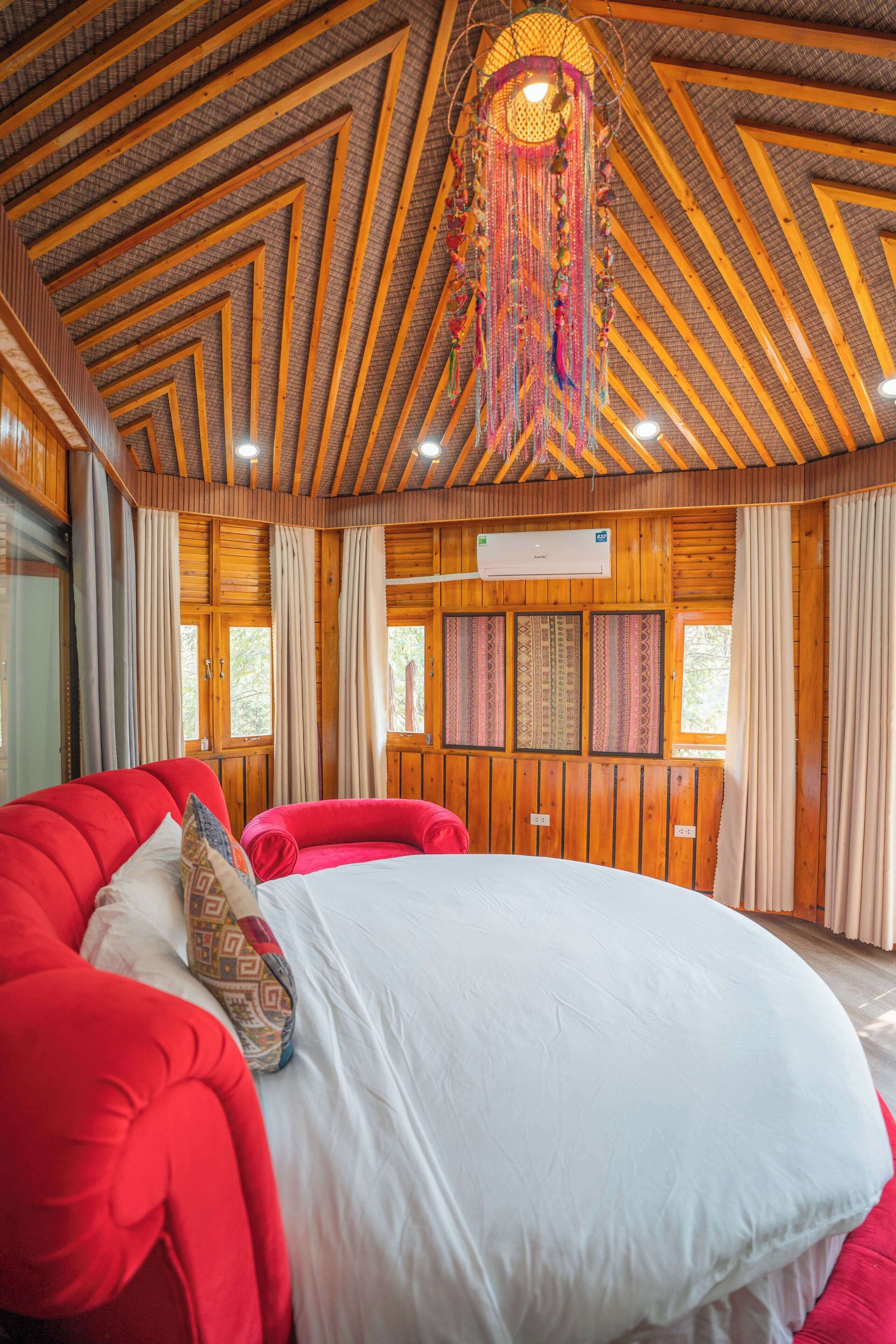 Een ruime slaapkamer met een groot bed, houten wanden en een schuin plafond met zichtbare balken.