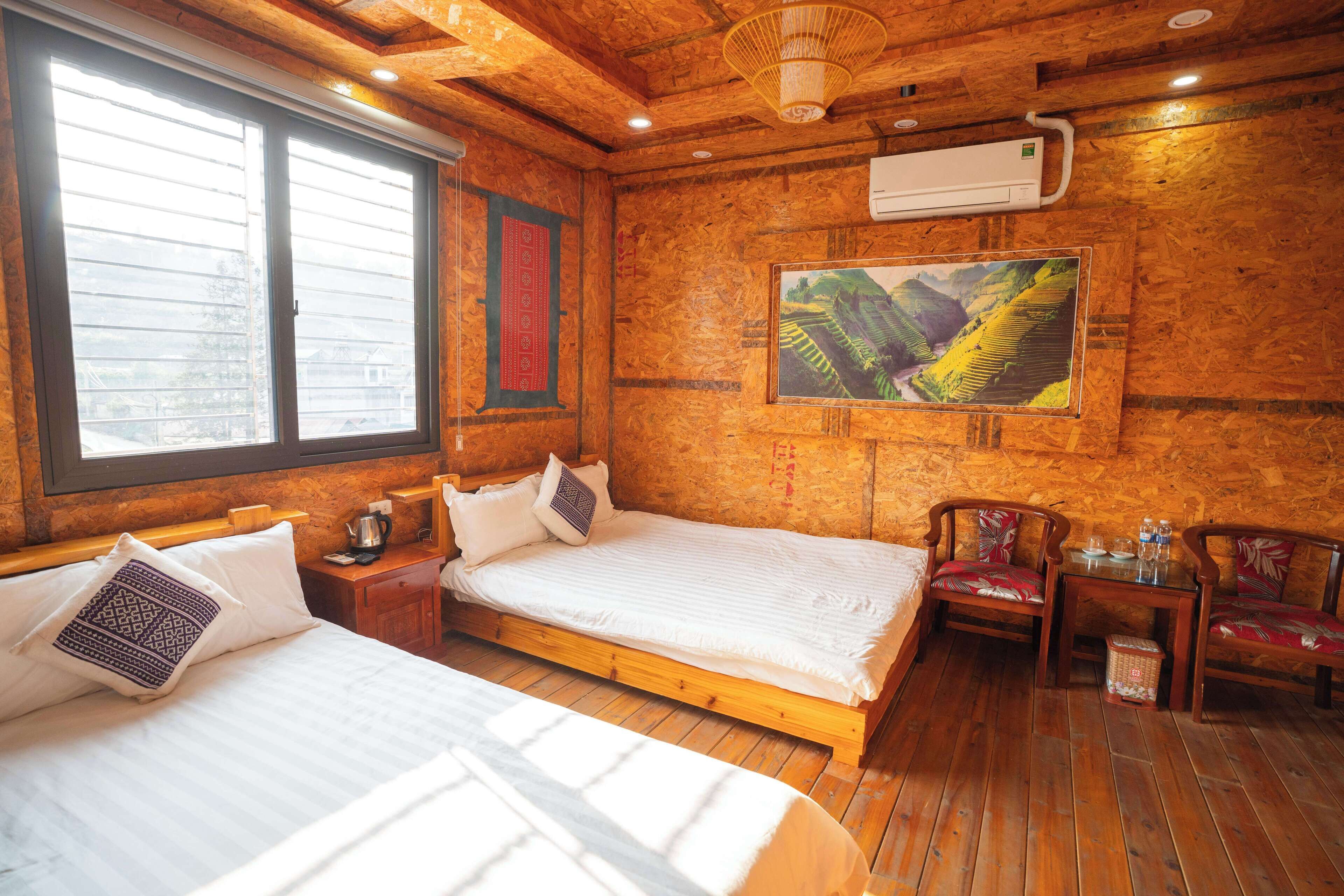 A wooden room with a bed, a table with chairs, and a painting on the wall.