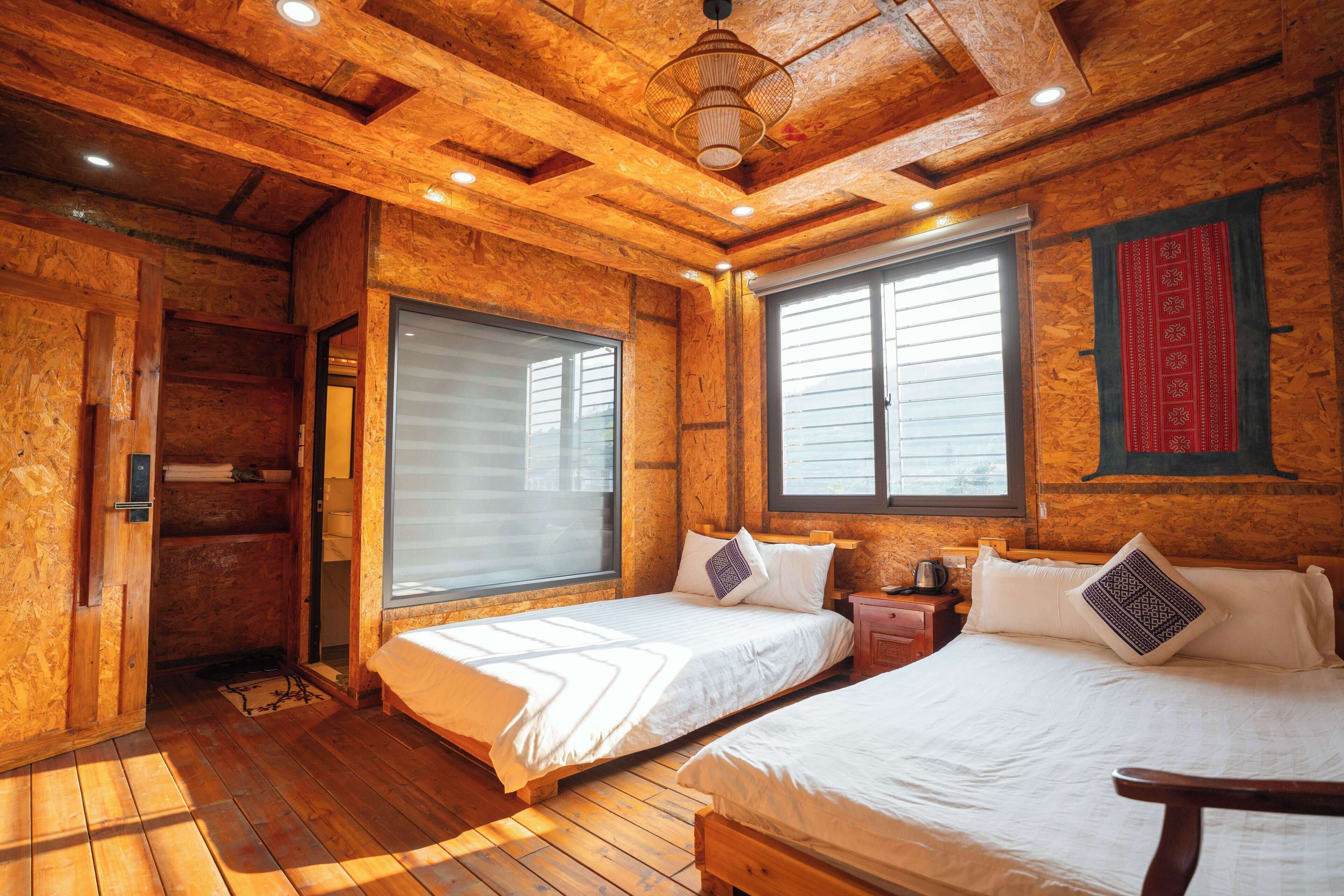 Ein holzgetäfelter Raum im Chalet-Stil mit zwei Betten, Holzboden und großen Fenstern.