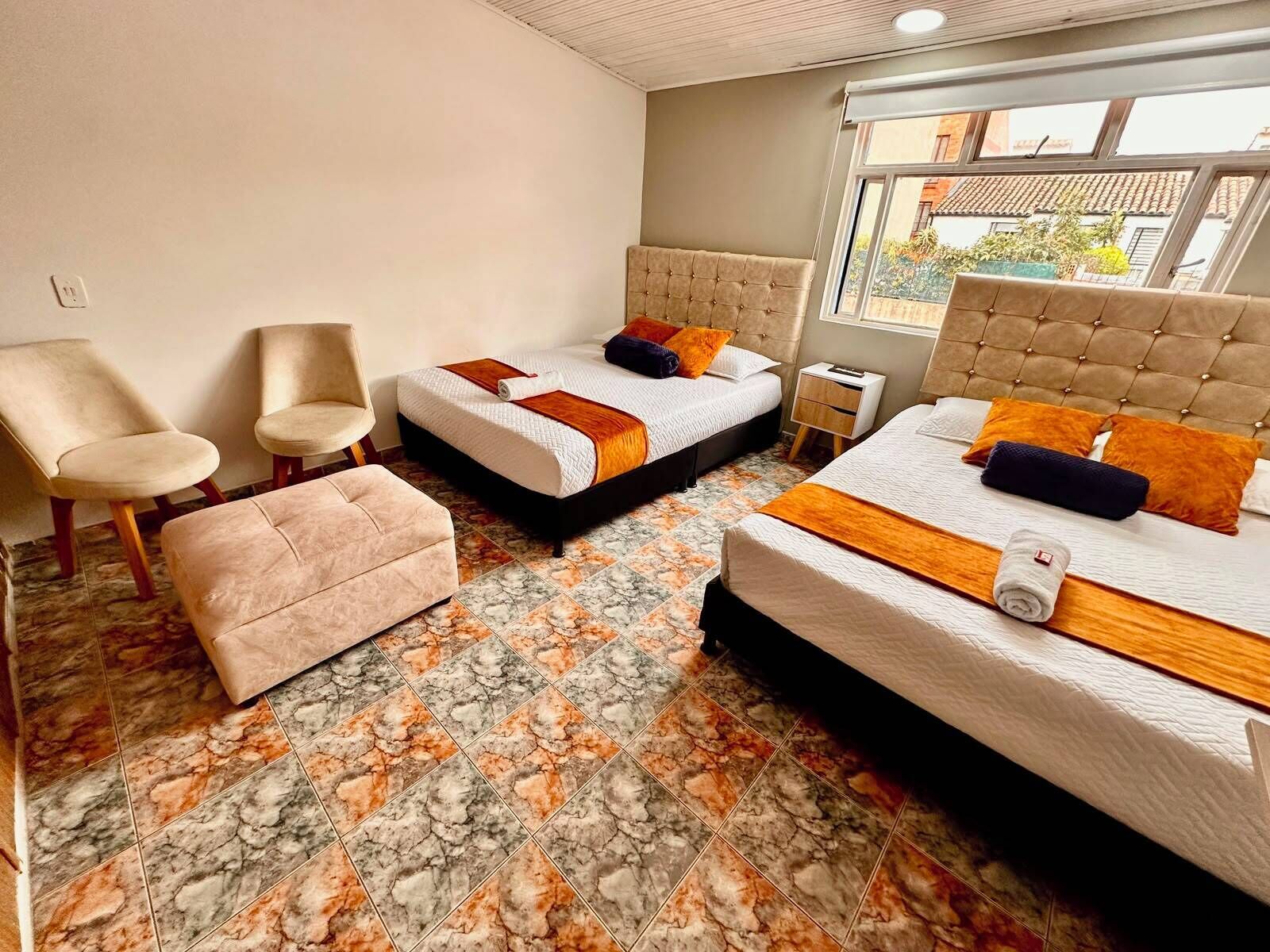 Une chambre d’hôtel avec deux lits, un coin salon et une fenêtre donnant sur un paysage agréable.