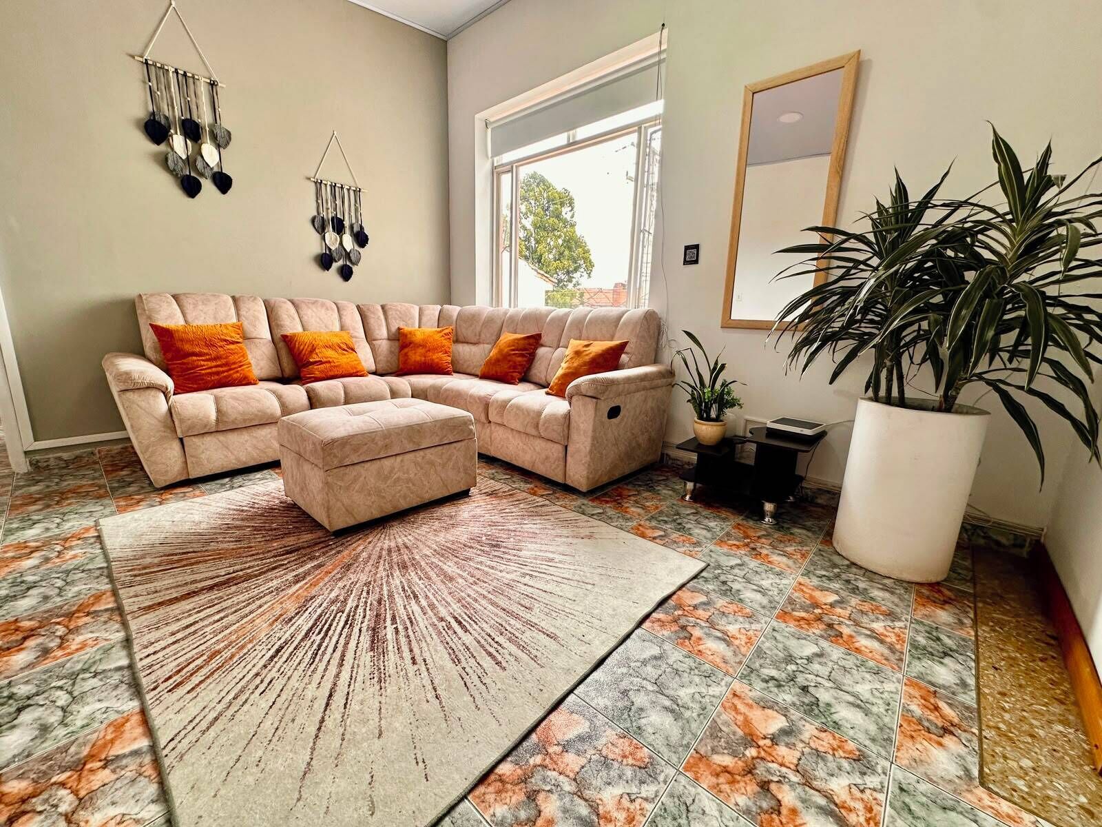Una sala de estar con sofá modular, reposapiés y una gran planta en maceta.
