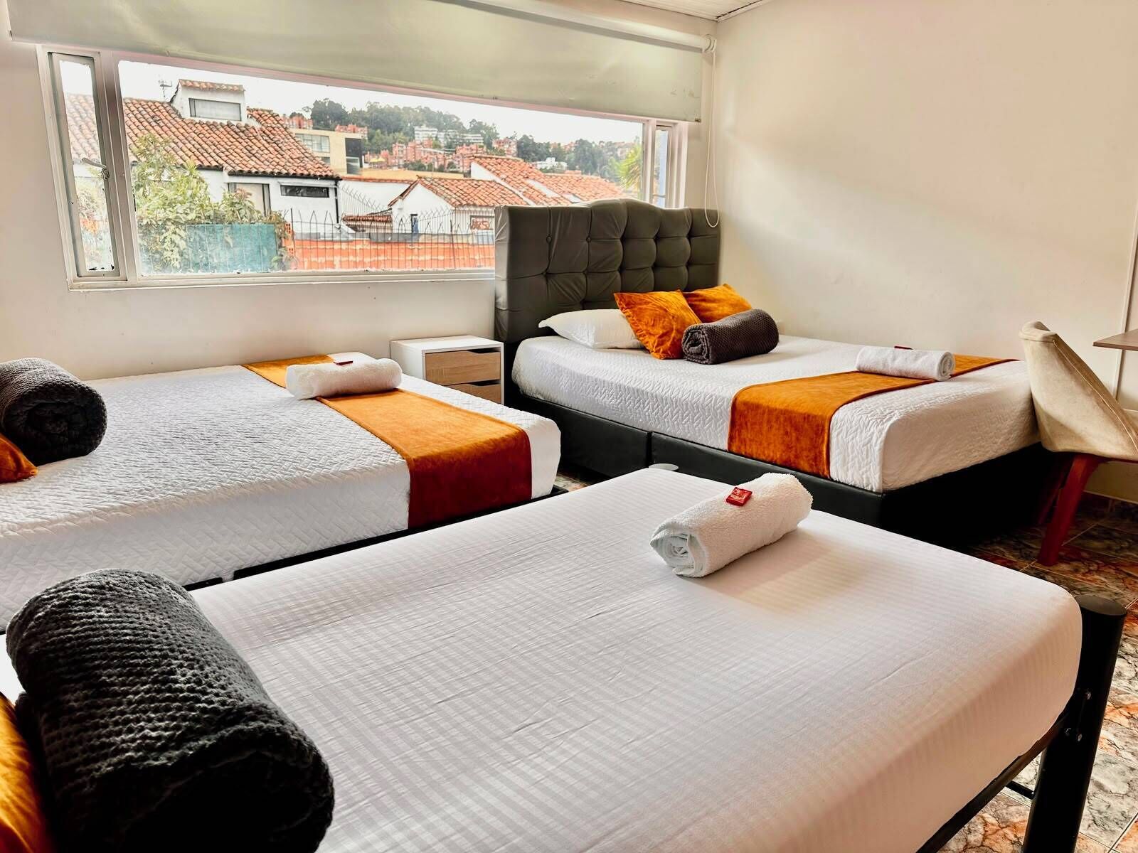 Ein Hotelzimmer mit zwei Betten, einem Fenster mit Blick auf Gebäude und einem Nachttisch.