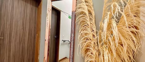Rincón de una habitación con un espejo, un tapete texturizado y una planta decorativa.