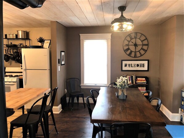A kitchen with a wooden table, chairs, a clock, and a 'WELCOME' sign.