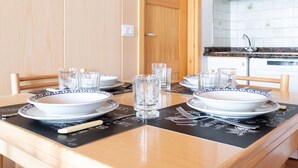 A dining table set with white plates, bowls, and clear glasses, with a black placemat featuring white text. - Bruni 2 - One Bedroom Apartment, Sleeps 3 (Bormio)