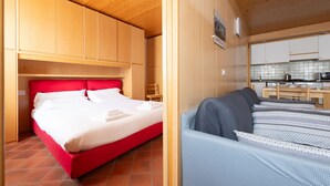 A compact room with a bed, a small seating area, and a kitchenette. - Bruni 2 - One Bedroom Apartment, Sleeps 3 (Bormio)