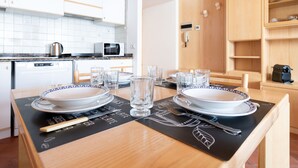 A dining table set with plates, glasses, and cutlery, with a kitchen in the background. - Bruni 2 - One Bedroom Apartment, Sleeps 3 (Bormio)