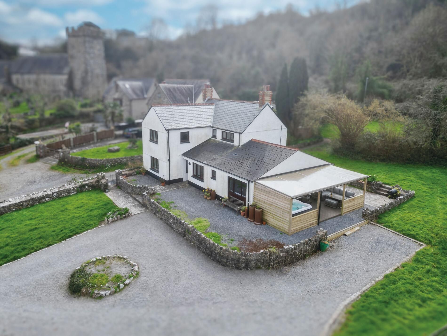 A model of a white two-story house with a sloped roof, a covered porch, and a small garden area.