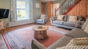 A living room with a sofa, a coffee table, and a television.