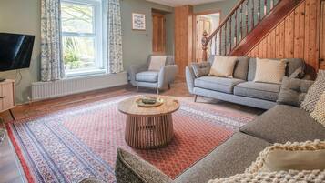 A living room with a sofa, a coffee table, and a television.
