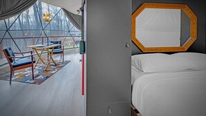 A bedroom with a bed, a large mirror, and a view of the outdoors. - Domes at Catskills a lakefront glamping adventure for adults (Swan Lake)
