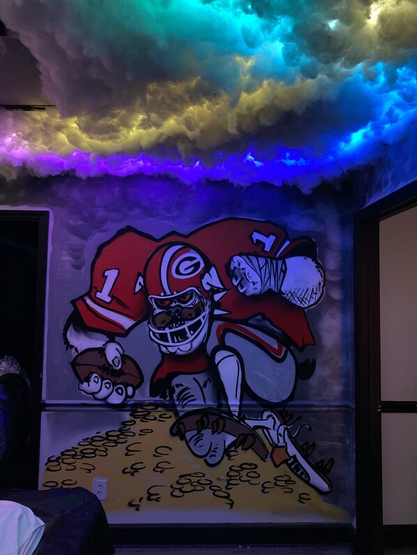 A mural of cartoon characters in a room with a ceiling that has a cloud-like design and colorful lighting. - K3soundz recording studio/ event space   (Decatur)