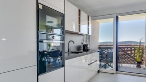 A modern kitchen with a large window, a dining area, and a view of the cityscape.