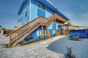 A two-story blue house with a wooden staircase leading to a balcony.