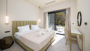 A modern hotel room with a large bed, a desk, and a view of the outdoors.