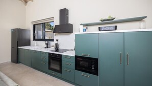 A modern kitchen with teal cabinets, a black refrigerator, a built-in oven, and a microwave.