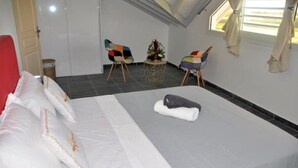 A hotel room with a bed, two chairs, a small table, and a window with curtains.