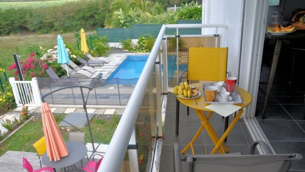 A balcony with a pool, outdoor seating, and a table with food and drinks.