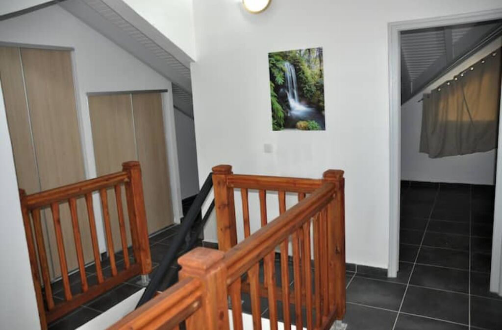 A staircase with wooden railings leading to a room with a tiled floor and a window with a curtain.