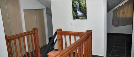 A staircase with wooden railings leading to a room with a tiled floor and a window with a curtain.
