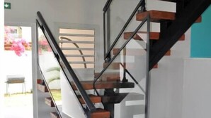 A modern staircase with glass railings and wooden steps, leading to an upper floor.