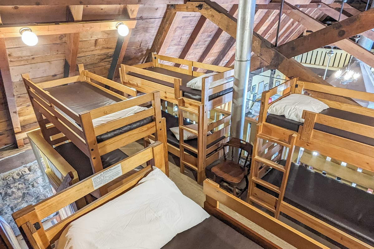 Un dormitorio con literas, una barra de metal y una escalera.
