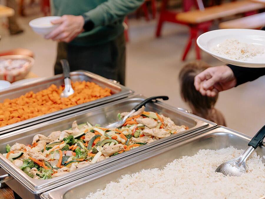 A buffet with various food options including rice, a chicken dish, and a vegetable stir-fry.