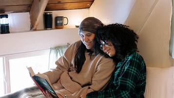 A cozy room with a wooden ceiling, a window, and a bed with a patterned blanket.