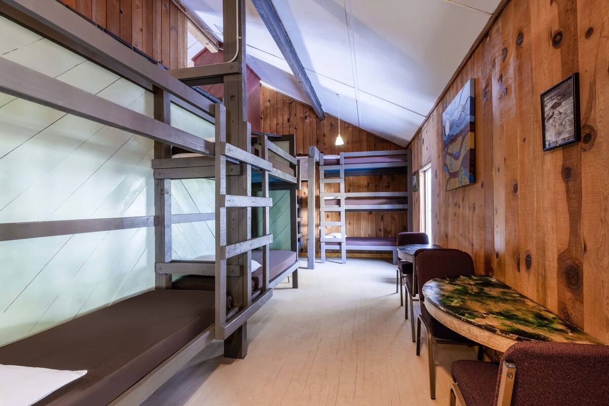 Habitación con literas, paredes de madera y zona de comedor.