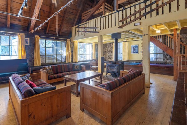 A cozy cabin interior with wooden furniture, a fireplace, and a loft area. - Clair Tappaan Lodge (Soda Springs)