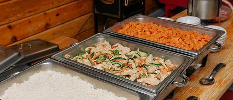 Ein Buffet mit verschiedenen Speisen, darunter Reis, Gemüse und Fleisch.